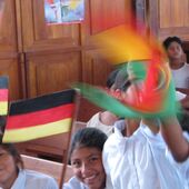 Eine Schulklasse in Bolivien schwenkt kleine Fahnen zur Begrüßung der Partnerschaftsgäste.