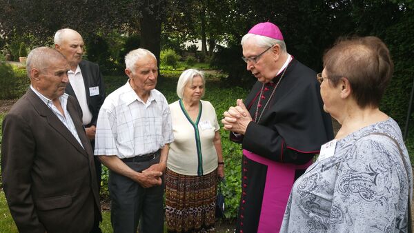 Bischof Norbert Trelle unterhält sich im Garten des Bischofshauses in Hildesheim mit weißrussischen KZ-Überlebenden. 