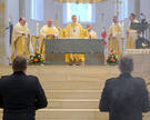 Blick zum Altar im Hildesheimer Dom, an dem Bischof Wilmer und weitere Geistliche stehen. Im Vordergrund sind in der Rückenansicht Angehörige von Polizei und Bundeswehr zu erkennen. 