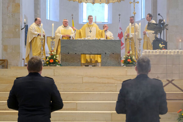 Blick zum Altar im Hildesheimer Dom, an dem Bischof Wilmer und weitere Geistliche stehen. Im Vordergrund sind in der Rückenansicht Angehörige von Polizei und Bundeswehr zu erkennen. 