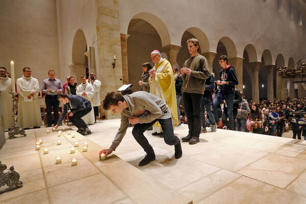 Jugendliche platzieren im Hildesheimer Dom für die Opfer der Brüsseler Anschläge Kerzen vor dem Altar, in der Mitte Bischof Norbert Trelle.