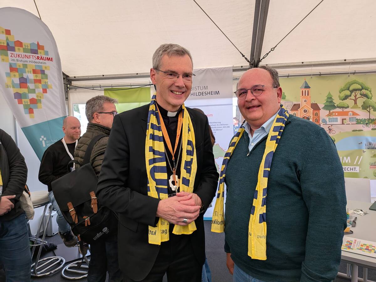Bischof Dr. Heiner Wilmer SCJ und Diözesanratsvorsitzender Dr. Christian Heimann treffen sich am Bistumsstand auf dem Katholikentag 2026. 