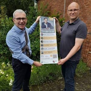 Detlef Brückner und Michael Peters zeigen das Programmplakat