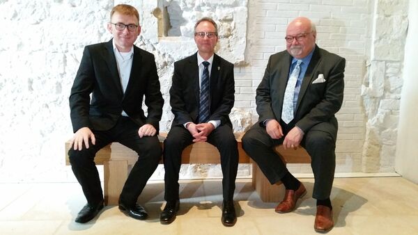 Domkapitular Martin Wilk, Jörg Bartels, Präsident des Lions-Club Hildesheim, und der Vorsitzende des Dombauvereins, Dr. Konrad Deufel, nehmen auf einer neuen Bank im Dommuseum Platz.