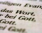 Eine Bibel liegt aufgeschlagen auf einem Tisch. Es sind die Worte "Wort" und "Gott" zu lesen.