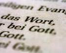 Eine Bibel liegt aufgeschlagen auf einem Tisch. Es sind die Worte "Wort" und "Gott" zu lesen.