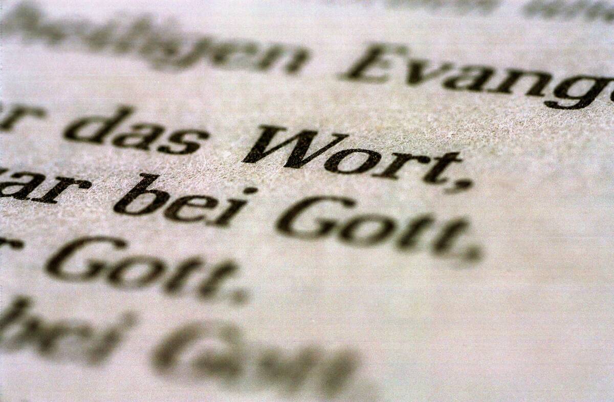 Eine Bibel liegt aufgeschlagen auf einem Tisch. Es sind die Worte "Wort" und "Gott" zu lesen.