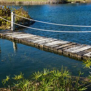 Brücke mit Handlauf zwischen zwei Inseln auf einem See