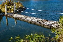 Brücke mit Handlauf zwischen zwei Inseln auf einem See