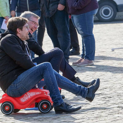 Der Bischof fährt vor im Bobbycar: Heiner Wilmer hat während des Vorprogramms zur Chrisammesse sichtlich Spaß auf dem Domhof.