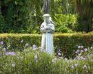 Eine Statue des hl. Franziskus von Assisi inmitten von Blumen und Bäumen