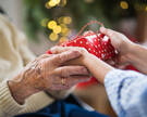 Close-up of hands of senior and young woman holding a present at Christmas.