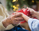 Close-up of hands of senior and young woman holding a present at Christmas.