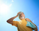 Senior man with towel suffering from heat stroke outdoors, low angle view